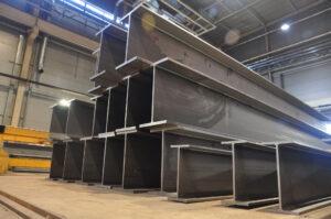 Structural steel beams stacked in a warehouse.