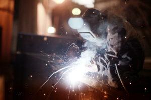 Worker in protective clothing cuttling structural steel