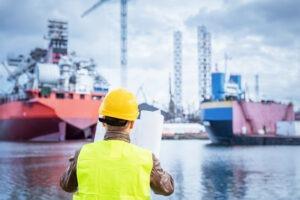 shipbuilder referencing documents against a moody sky