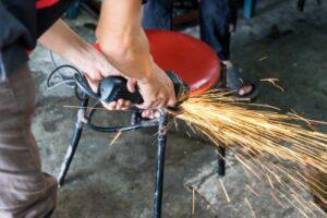 A man is using a grinder to sharpen a chair.