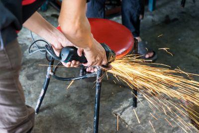 A man is using a grinder to sharpen a chair.