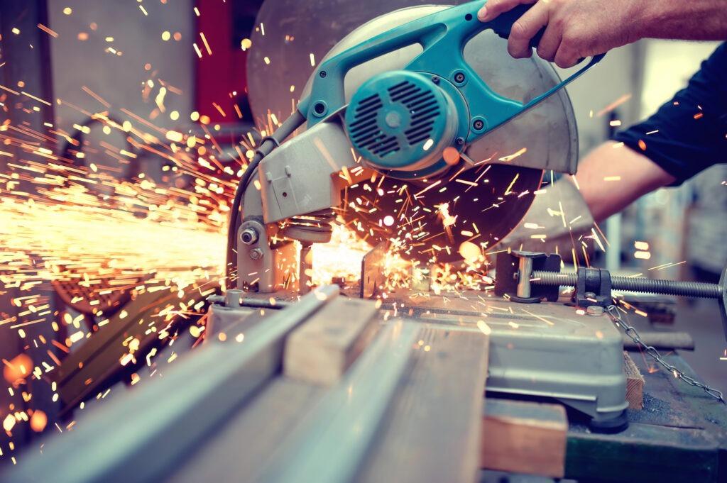 Worker cutting a steel bar with sparks from a circular saw